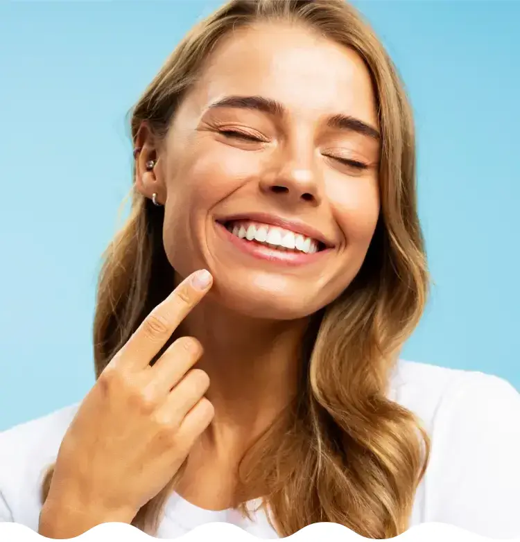 A cheerful woman who is smiling and pointing at her strong teeth.